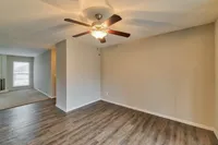 Inviting living space with stylish wooden flooring, ceiling fan, and ample natural light from large window.