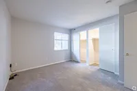 Bright and airy bedroom with plush carpeting, large window for natural light, and spacious dual closets.