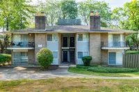 Charming two-story apartment building with spacious balconies and lush green surroundings.