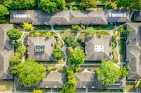 Aerial view of a beautifully organized apartment complex surrounded by lush green trees, showcasing well-maintained pathways and inviting communal spaces.