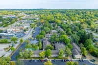 Stunning aerial view of a vibrant apartment complex surrounded by lush greenery and ample parking, offering a serene and convenient lifestyle.