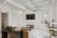 Modern office space with sleek marble flooring, contemporary seating, and a wall-mounted TV offering an inviting and professional atmosphere.