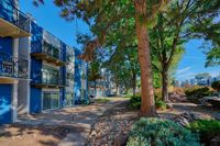 Charming apartment complex with vibrant blue accents, surrounded by lush greenery and serene pathways.