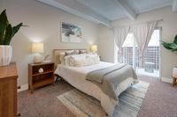 Inviting bedroom with cozy white bedding, modern wooden furniture, elegant decor, and abundant natural light from large windows.