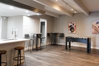 Modern game lounge with a sleek bar area, foosball table, and contemporary seating.