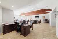 Elegant office space with rich wooden furniture, bright natural lighting, and a cozy lounge area, perfect for a productive and comfortable work environment.