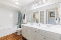 Bright and elegant bathroom featuring double sinks, a modern vanity, and stylish fixtures complemented by a serene bathtub setting.