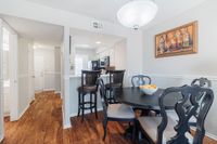 Inviting dining area with elegant dark wood furniture, open kitchen with bar seating, and rich wood flooring, perfect for gatherings.