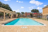 Inviting apartment community pool with sun loungers, pergola, and vibrant umbrellas, perfect for relaxation.