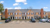 Charming townhouse complex with inviting brick accents, ample parking, and a serene suburban setting.