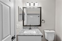 Elegant bathroom with a sleek granite countertop, modern vanity mirror, and chic subway tile shower.