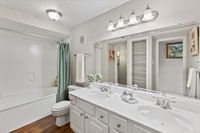 Elegant bathroom featuring a double vanity with marble countertops, ample storage, and a cozy bathtub with a stylish curtain.