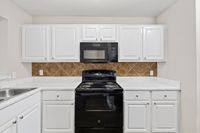 Modern kitchen featuring sleek white cabinetry, elegant marble countertops, and stylish black appliances.