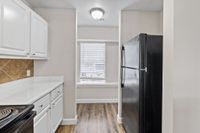 Modern kitchen with sleek black appliances, white cabinetry, and sunlit window for a bright, inviting space.