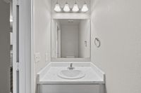 Elegant bathroom vanity with a sleek marble countertop, large mirror, and modern lighting fixture.