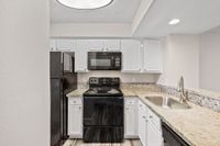 Modern kitchen with sleek granite countertops, stainless steel sink, and stylish black appliances.