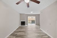 Bright living room with elegant wood-look tile flooring, cozy fireplace, and sliding doors leading to a private outdoor space.