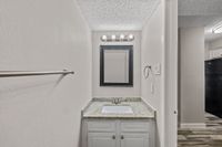 Bright bathroom with modern black framed mirror, elegant granite countertop, and stylish light fixtures.