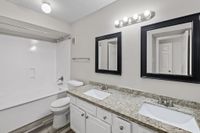 Elegant modern bathroom with dual sinks, granite countertop, and bright lighting.