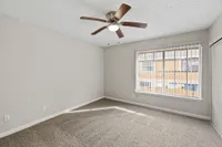 Bright and spacious bedroom with plush carpet, a modern ceiling fan, and large window inviting ample natural light.