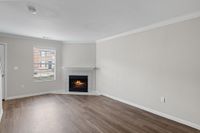 Inviting living room with elegant hardwood flooring, a cozy fireplace, and ample natural light through a large window.
