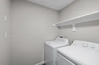 Modern laundry room with sleek washer and dryer, featuring a convenient wall-mounted shelf for storage.