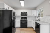 Modern kitchen with sleek black appliances, granite countertops, and stylish white cabinets for a contemporary feel.