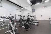 Modern fitness center featuring state-of-the-art exercise equipment, including treadmills and stationary bikes, with a sleek mirrored wall and bright lighting.