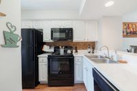 Contemporary kitchen with sleek black appliances, elegant white cabinetry, and a spacious countertop perfect for cooking and entertaining.