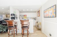 Bright apartment interior featuring a cozy breakfast bar with elegant wooden chairs, a modern coffee maker, and a stylish white kitchen backdrop.