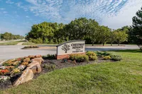 Welcoming entrance to Chestnut Heights with vibrant landscaping and clear skies, highlighting a serene suburban setting.
