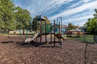 Charming community playground with vibrant equipment set on a sunny day surrounded by lush greenery and a cozy gazebo.