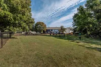 Spacious fenced yard with lush greenery and playground, perfect for family recreation and enjoying sunny days.