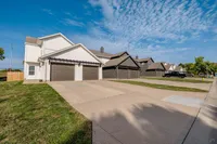 Charming suburban street lined with modern duplexes featuring clean driveways and well-maintained lawns under a vibrant blue sky.