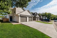 Charming suburban duplex with modern garages, set in a lush, green neighborhood under a bright, blue sky.