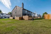 Charming row of townhouses with private fenced yards, set against a clear blue sky and lush green lawn.