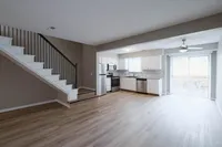 Modern open-concept kitchen with sleek white cabinetry, stainless steel appliances, and bright sliding glass doors leading to a scenic outdoor space.