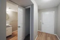 Inviting apartment entryway featuring modern white doors, warm wooden floors, and a cozy bathroom with stylish fixtures.