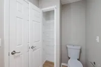Bright apartment bathroom featuring sleek white fixtures and a convenient built-in storage closet.