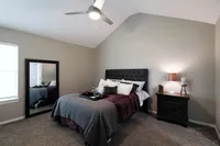 Inviting bedroom with vaulted ceiling, elegant tufted headboard, plush pillows, and a cozy ambiance.