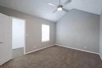 Elegant room with a high ceiling, modern ceiling fan, and plush carpet, perfect for a cozy and inviting atmosphere.