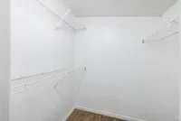 Spacious walk-in closet with sleek white shelving and plush carpeting, perfect for organized storage in a modern apartment.