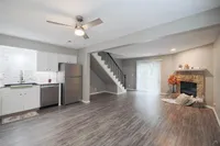 Modern open-concept living space with sleek kitchen, elegant staircase, and cozy fireplace featuring chic wood flooring.