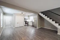 Modern open kitchen and living space with sleek stainless steel appliances and elegant staircase in a bright, airy apartment.