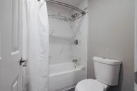 Elegant bathroom with a modern white bathtub and marble tile accents, complemented by a stylish shower curtain.