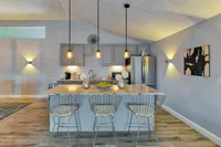 Modern kitchen interior with elegant pendant lighting, sleek stainless steel appliances, and a chic marble countertop with stylish bar seating.