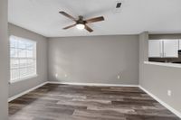 Bright and modern living area with sleek flooring, large window, and open access to a contemporary white kitchen.