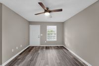 Bright, modern living space featuring sleek wood flooring, fresh neutral walls, and a contemporary ceiling fan.