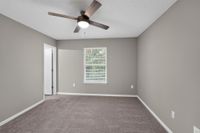 Bright and inviting bedroom with plush carpeting, large window, and modern ceiling fan.