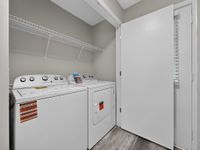 Modern laundry room featuring top-of-the-line washer and dryer with ample shelving, styled in a sleek, minimalistic design.